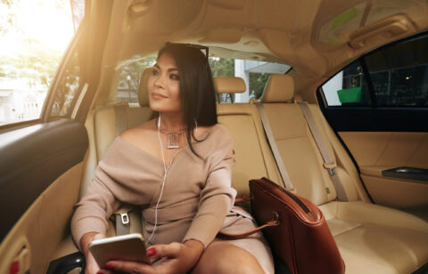 Portrait of beautiful smiling woman sitting on backseat in taxi