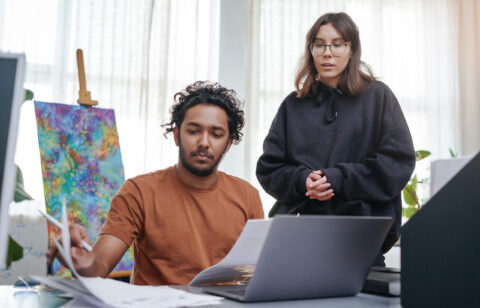 Professional businesspeople does their work together and plan at table in modern office. Caucasian and indian designer and their project.